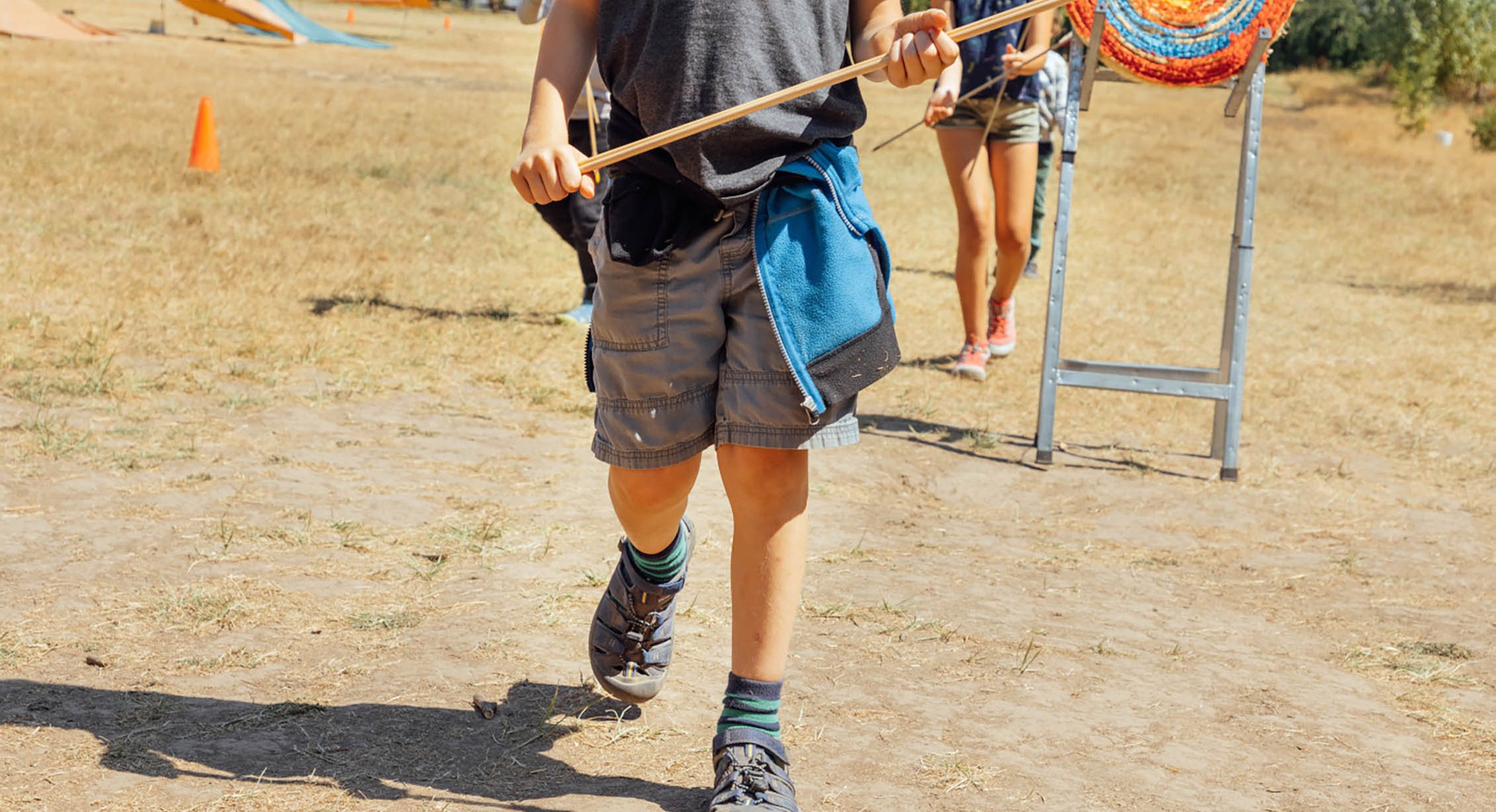 A kid doing archery at camp