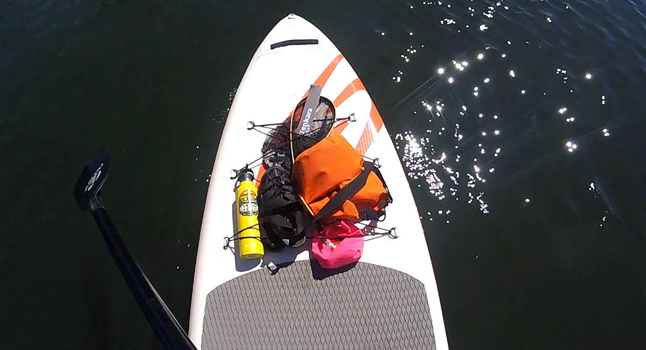 Stand-up paddleboarding with KEEN sandals and a reusable water bottle